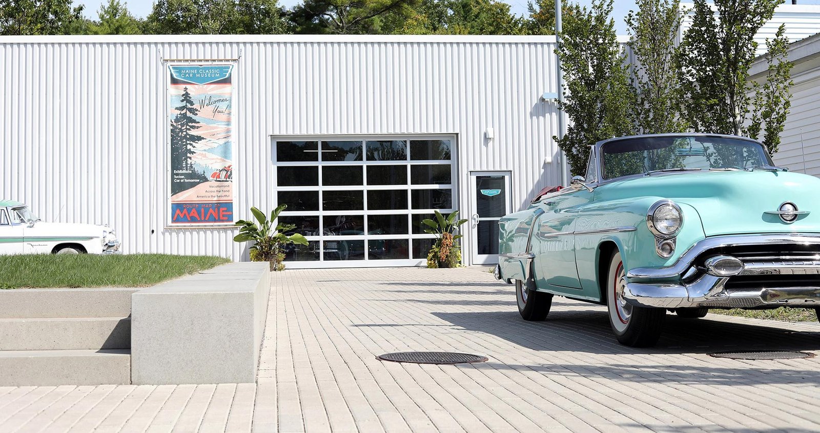 A blue car is parked in front of a modern building, showcasing its vibrant color against the architectural backdrop.